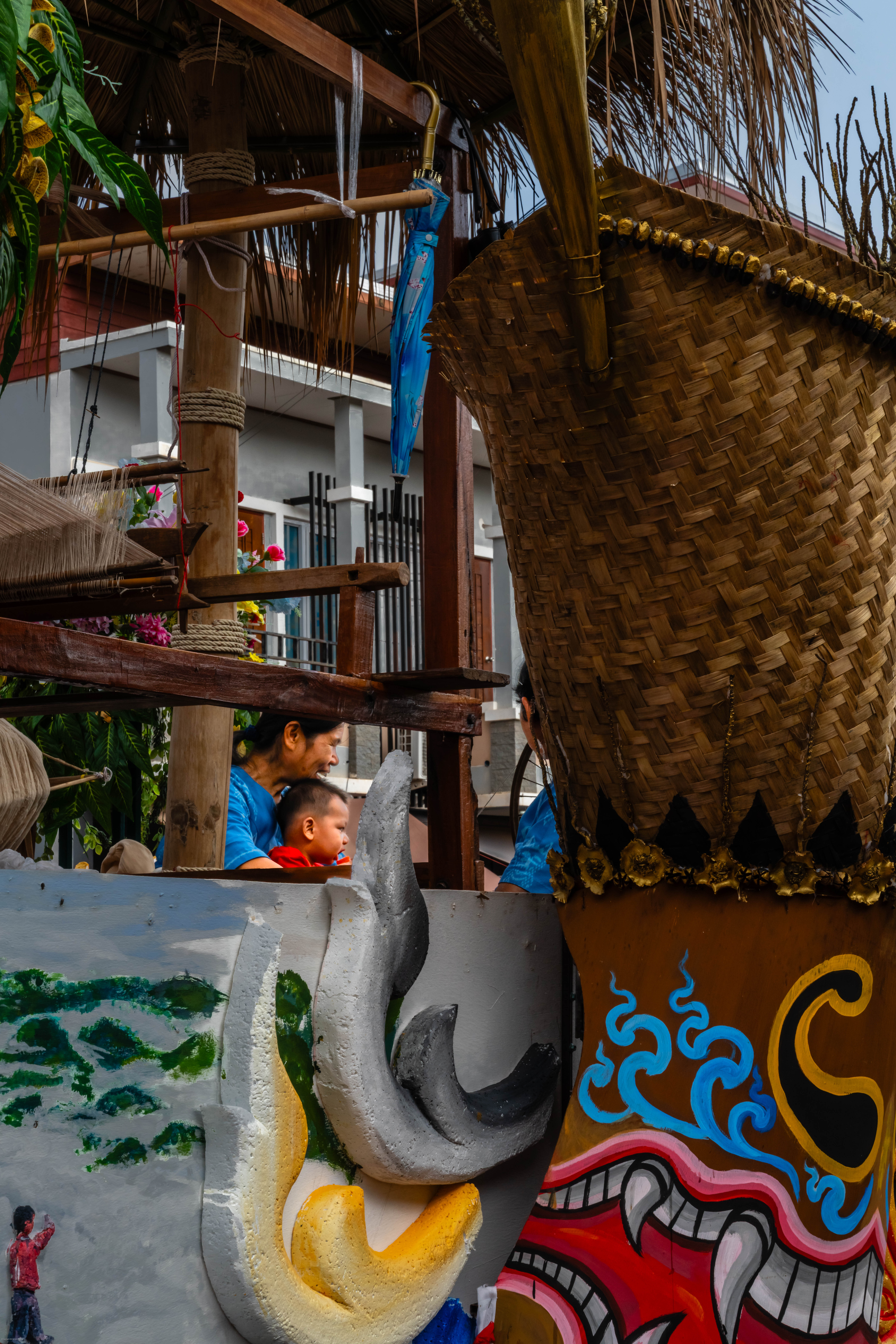 Mother and child seen through the frame of a Phi Ta Khon float