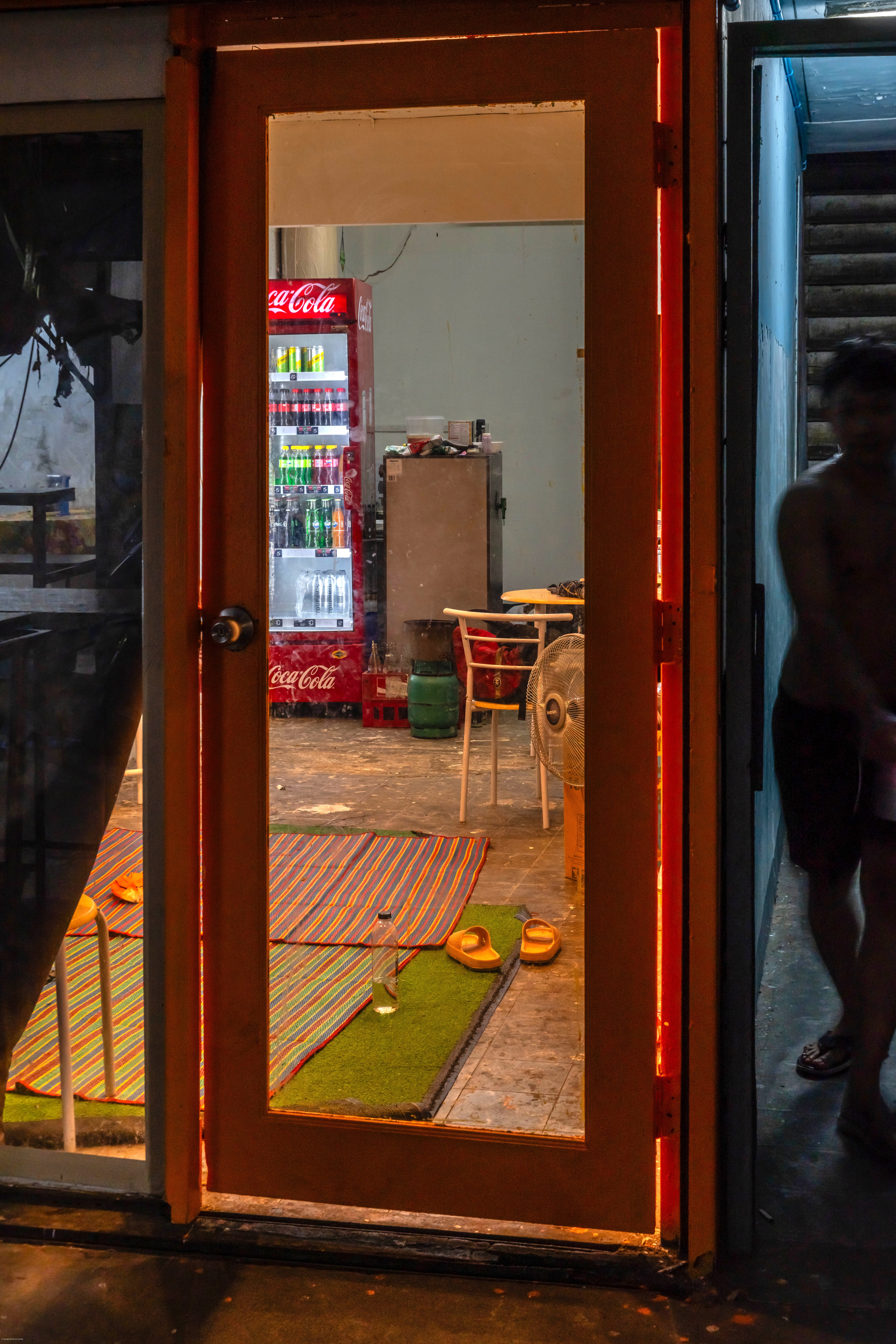 A figure appears coming down the stairs in a dark hallway