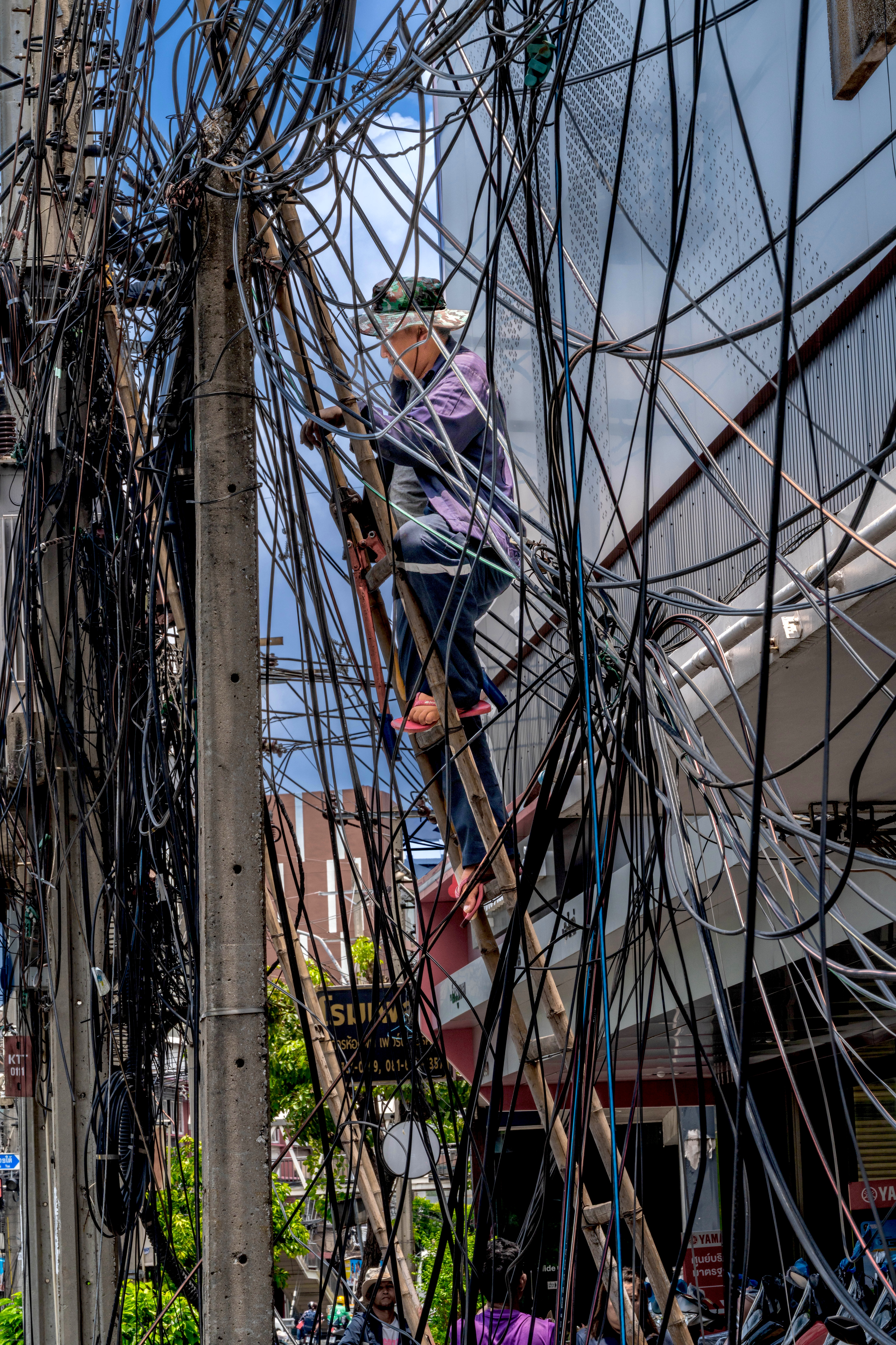Workman climbing pole to work on telephone wires.