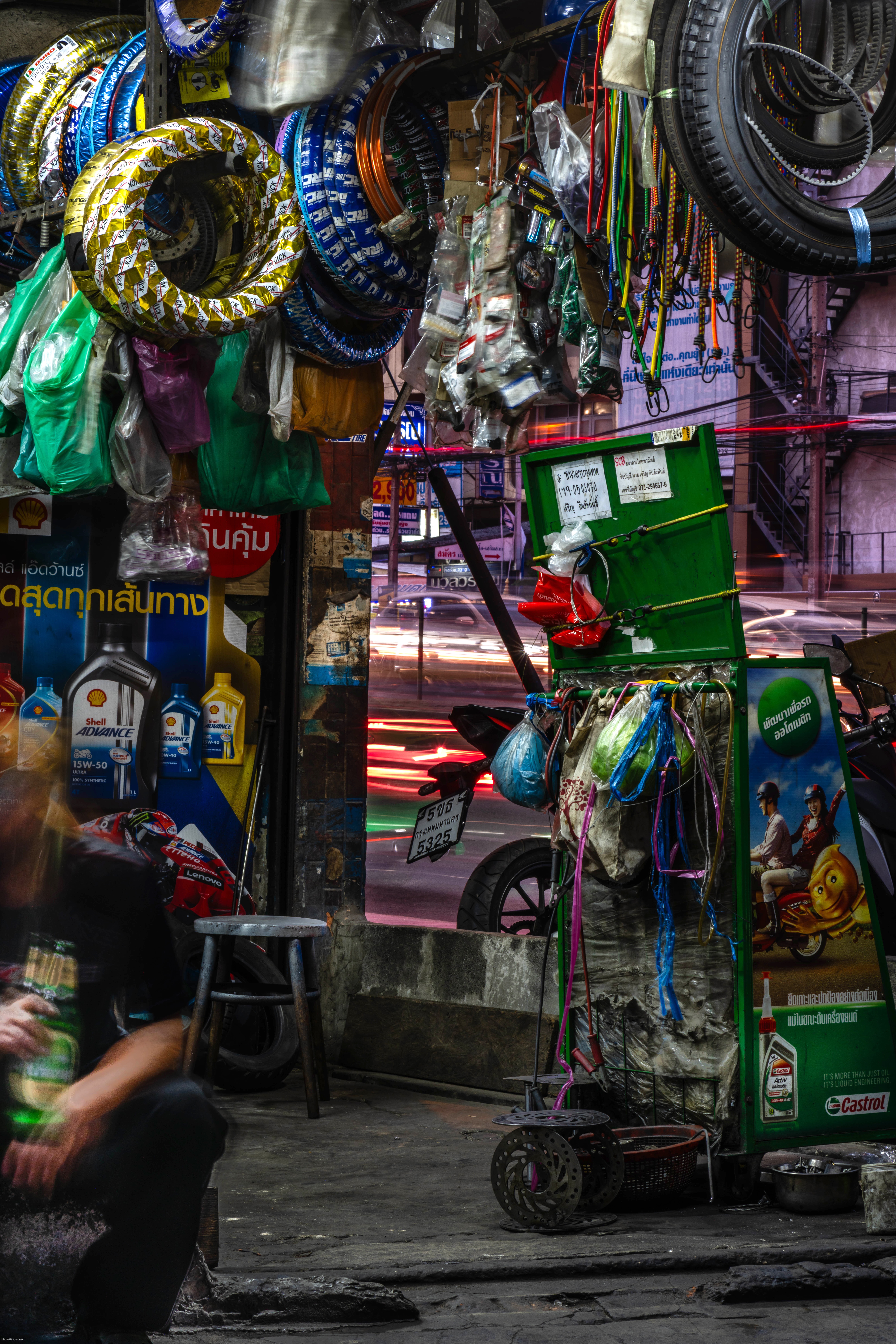 A man sits in a tire shop, holding a beer.