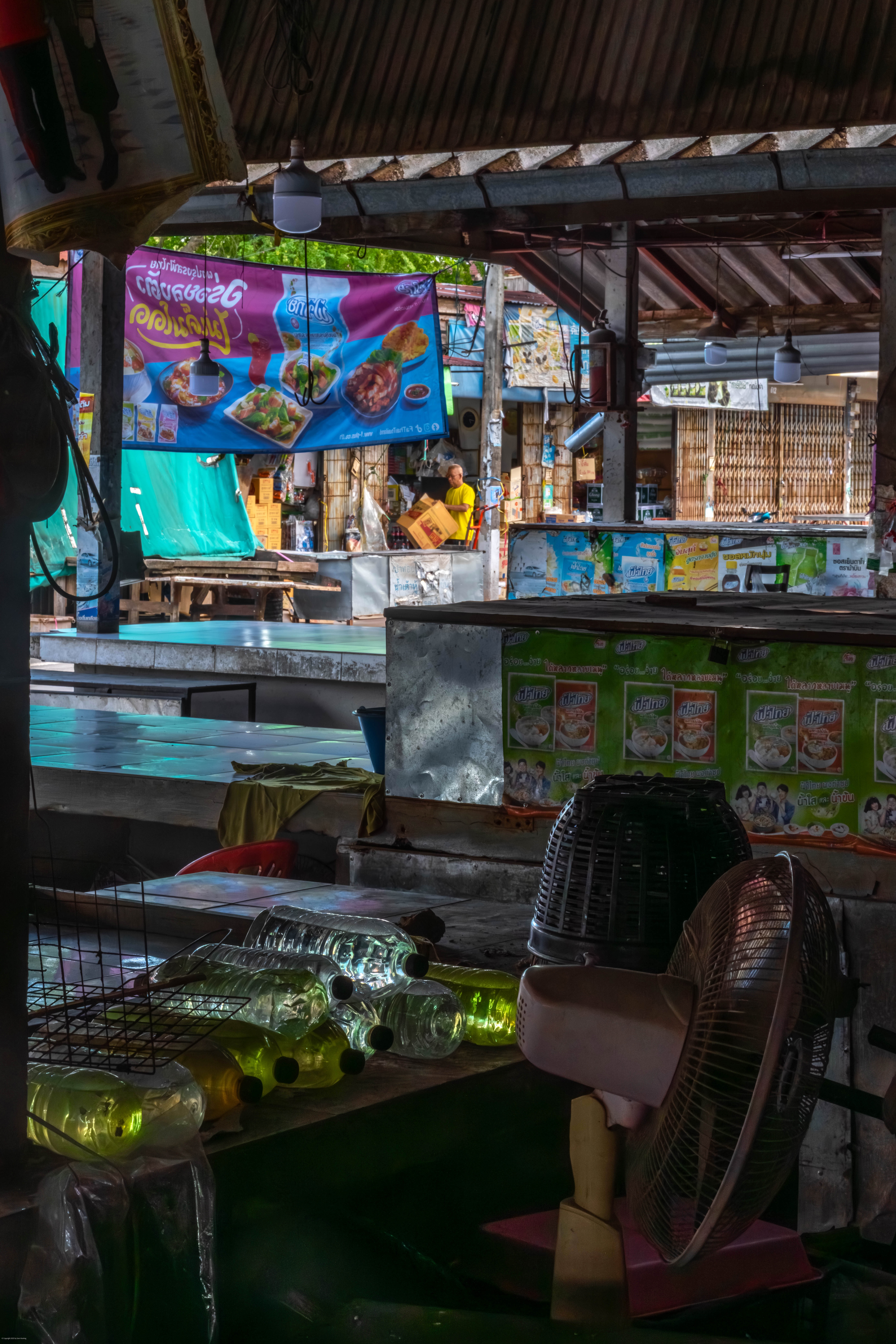 A man tearing up boxes, seen through a darkened market.