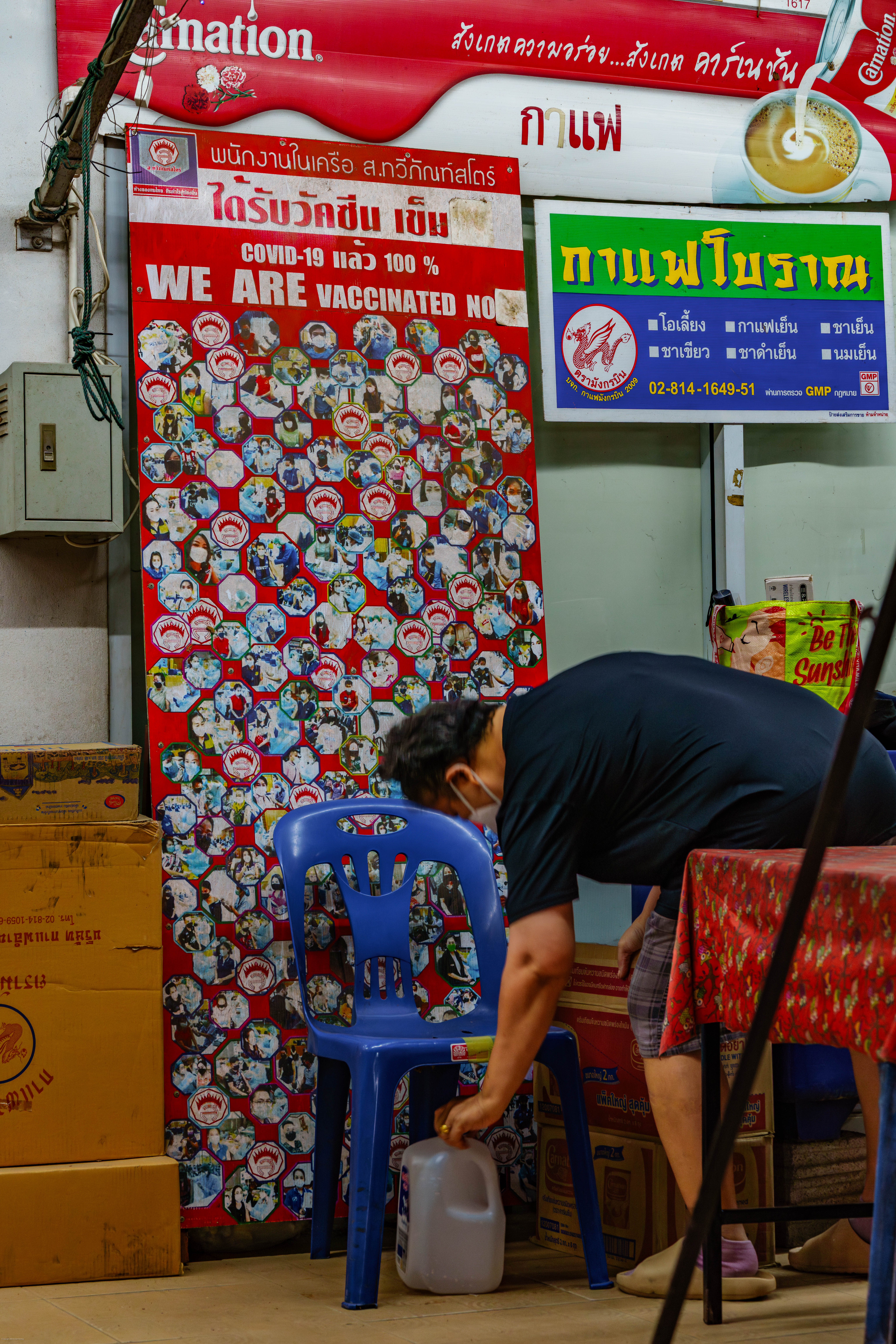 Restaurant worker beside a poster of people vaccinated during Covid.